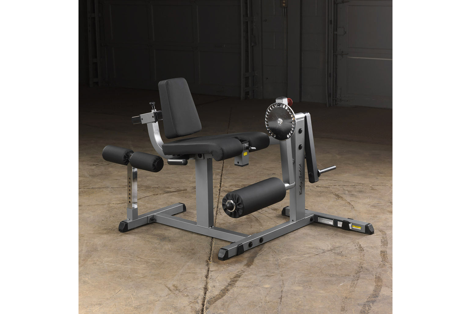 Body-Solid leg extension and curl machine with gray steel frame, black padded seat and leg pads, adjustable weight plate sele