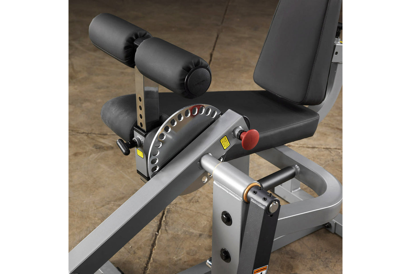 Body-Solid leg extension and curl machine with black padded seat, dual cylindrical leg rollers, silver frame, red adjustment 