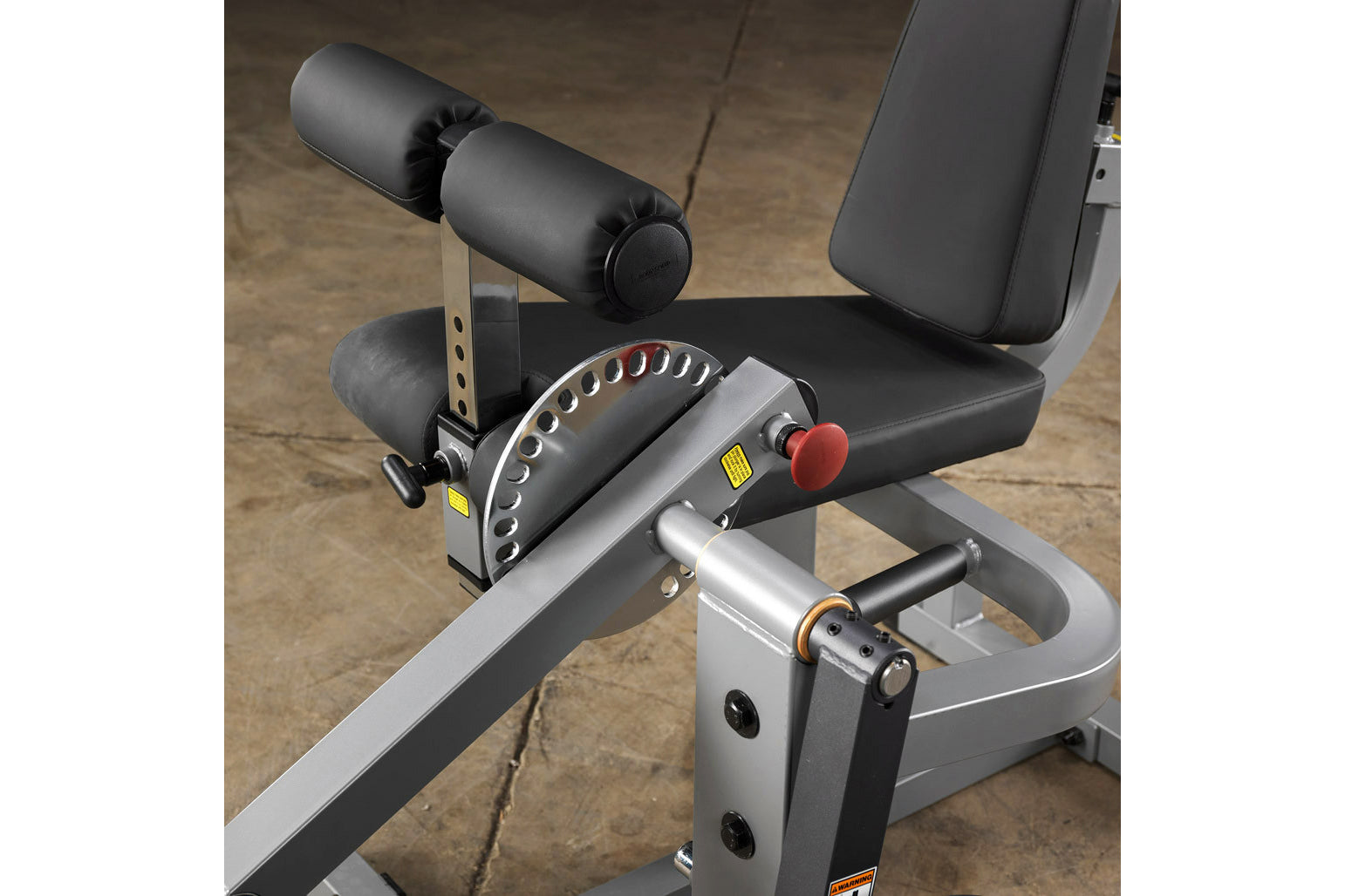 Body-Solid leg extension and curl machine with black padded seat, dual cylindrical leg rollers, silver frame, red adjustment 