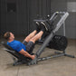 Body-Solid leg press and hack squat machine in gray and black with weighted footplate, shown in use by model in gym