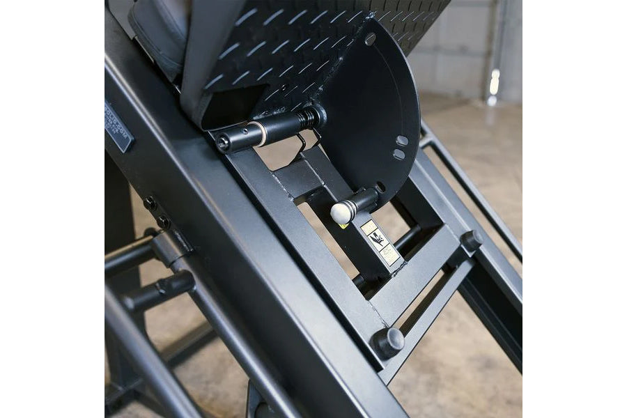 Close-up of black Body-Solid leg press machine showing foot pedal, adjustment lever, and metal frame details
