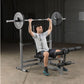 Man using gray and black weight bench with barbell and black weight plates in gym setting
