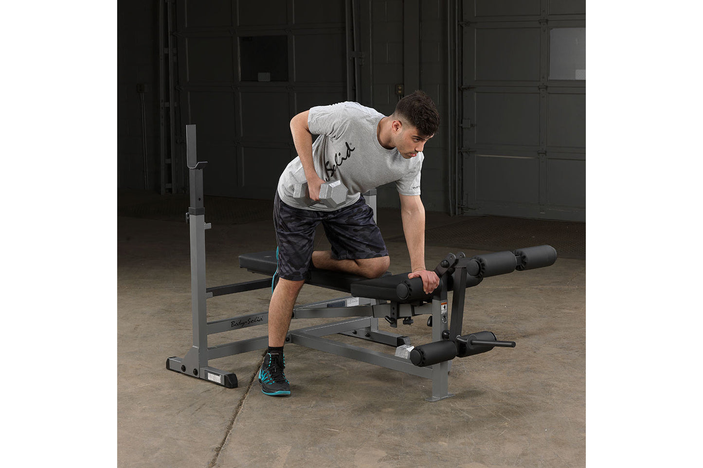 Man using gray Body-Solid PowerCenter Combo Bench with leg extension attachment in gym setting