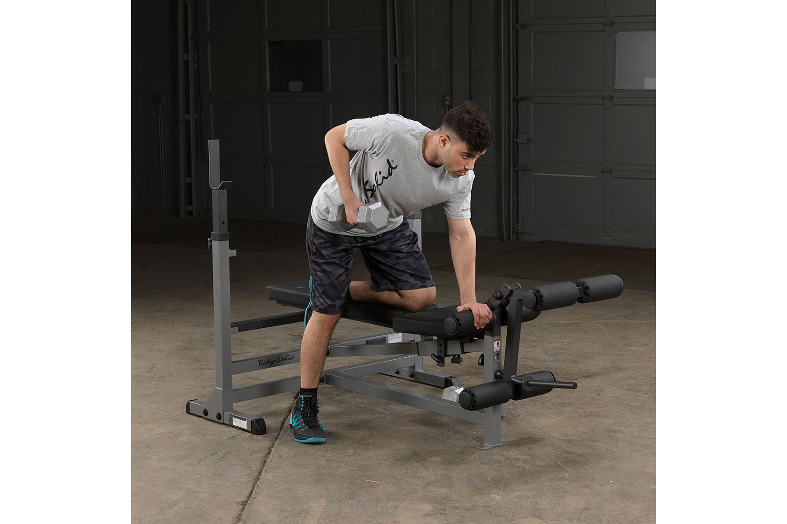 Man using gray Body-Solid PowerCenter Combo Bench with leg extension attachment in gym setting