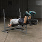 Man performing leg press exercise on gray Body-Solid PowerCenter Combo Bench with leg extension attachment in gym setting