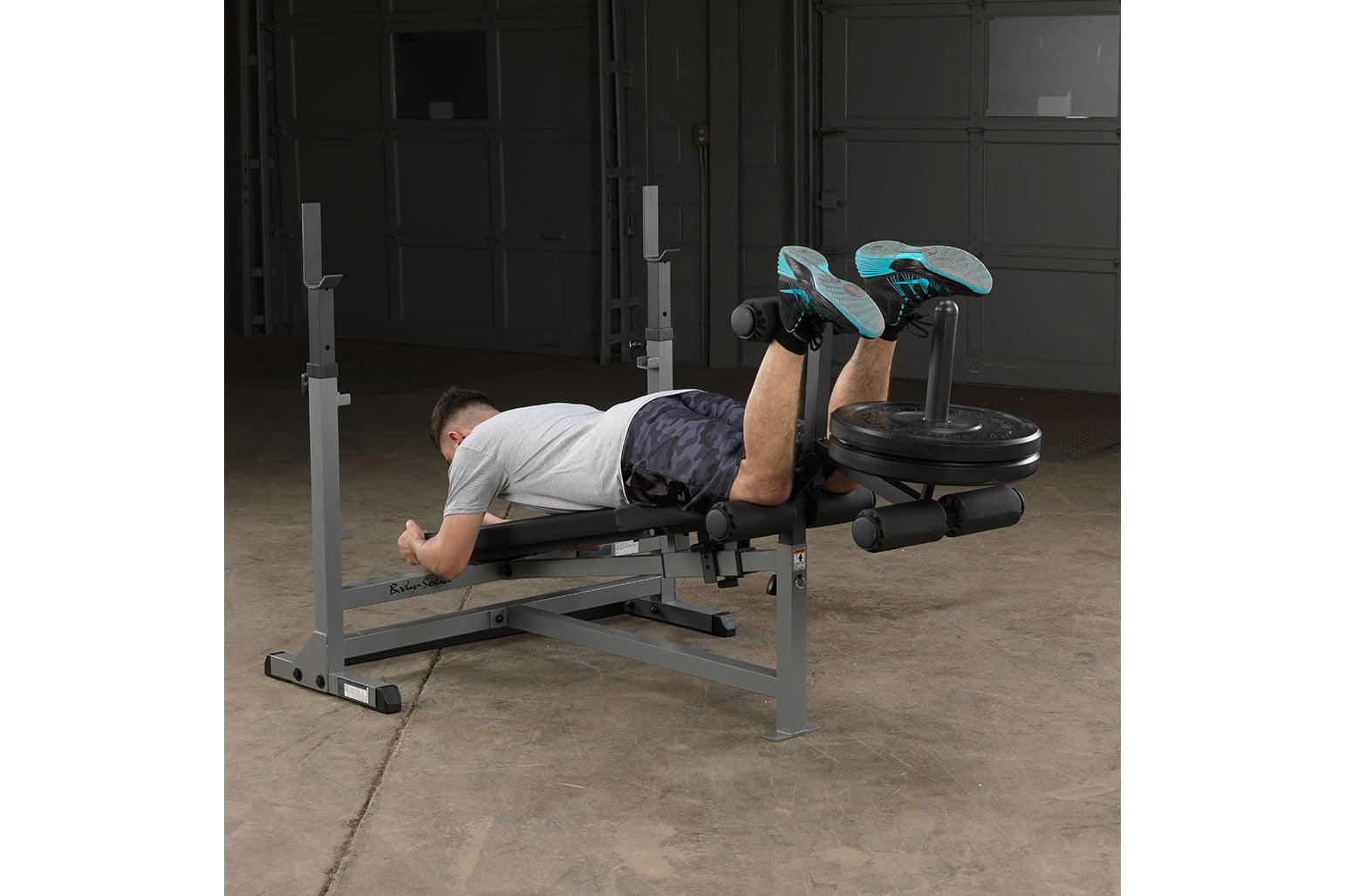 Man performing leg press exercise on gray Body-Solid PowerCenter Combo Bench with leg extension attachment in gym setting