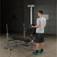 Body-Solid PowerCenter Combo Bench with barbell attachment, gray steel frame and black seat, worn by male model in garage gym