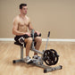 Man demonstrating Body-Solid PowerLine Seated Calf Raise Machine with gray frame and black weight plate on wooden floor