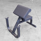 Body-Solid preacher curl bench with gray padded seat and backrest, black steel frame with leg extension, on concrete floor