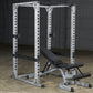 White metal power rack with perforated uprights and adjustable weight bench with black padding in garage setting