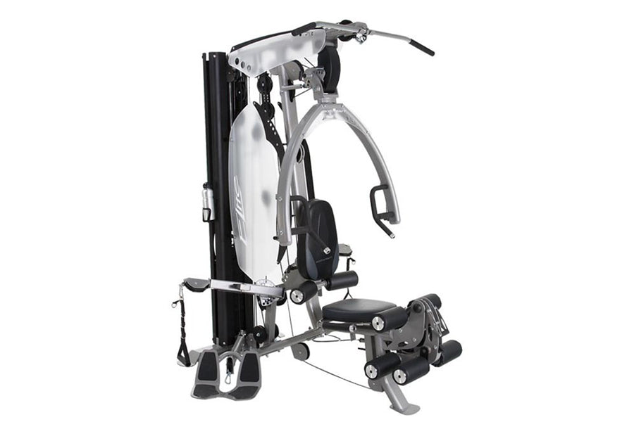 White and black multi-station home gym machine with adjustable weight stack, seat, and leg press attachment on white backgrou