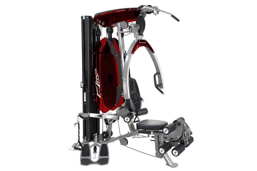 BodyCraft Elite home gym with red and silver frame, chest press station, leg extension attachment, and black seat on white ba