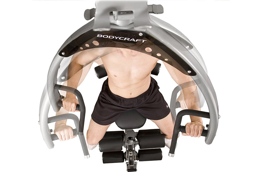 BodyCraft Elite home gym with gray frame and black padding, shown from above with shirtless male model demonstrating seated e