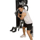 Man using black and gray home gym strength machine with white tank top and black shorts on white background