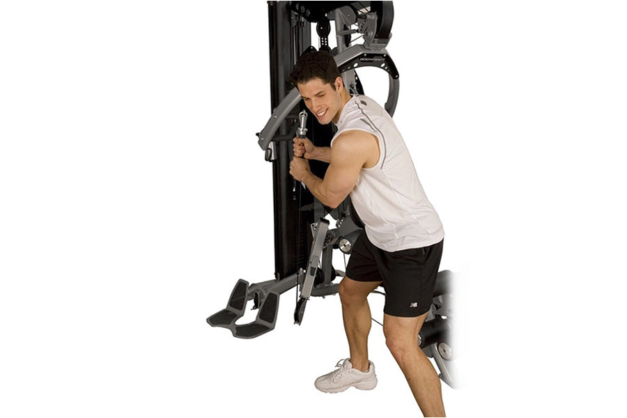 Man using black and gray home gym strength machine with white tank top and black shorts on white background