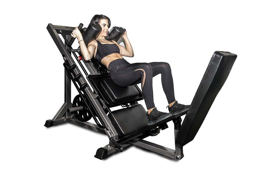 Woman using black BodyCraft Pro Leg Press machine with extended leg platform, holding upper handles during exercise demonstra