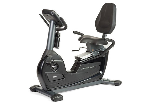 BodyCraft R200 semi-recumbent exercise bike with black seat, gray frame, digital console, and foot pedals on white background