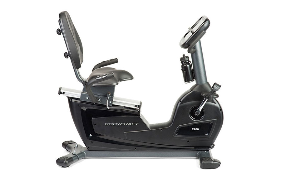 BodyCraft R200 semi-recumbent exercise bike with black frame, gray padded seat and backrest, digital display console, and foo