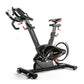 Black and gray stationary exercise bike with curved handlebars, adjustable seat, and resistance wheel on white background