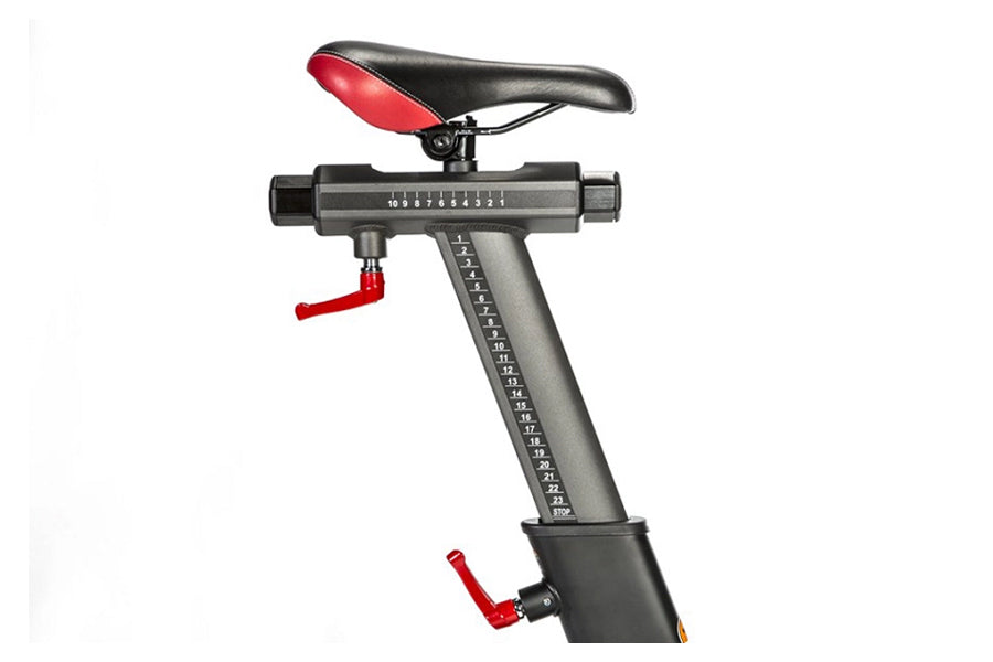 Stationary exercise bike with black and red seat, gray resistance column with measurement markings, and red adjustment handle