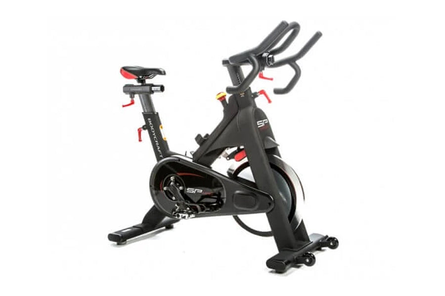 Black indoor training cycle with red accents, dual handles, red seat, and fixed wheelbase on white background