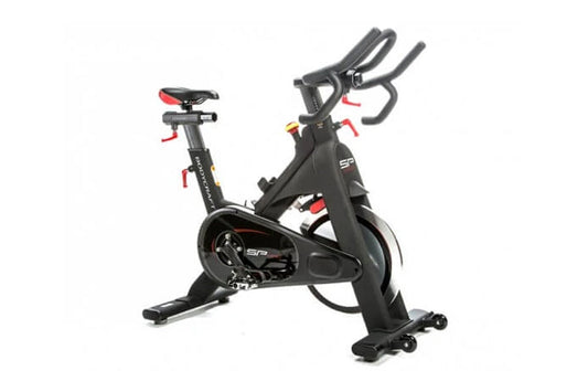 Black indoor training cycle with red accents, dual handles, red seat, and fixed wheelbase on white background