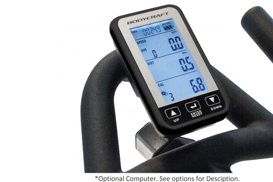 Bodycraft SPT-Mag stationary bike console with blue LCD display showing workout metrics, mounted on black handlebar, held by 
