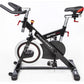 Black and red indoor training cycle with curved handlebars, padded seat, and stabilizer base on white background