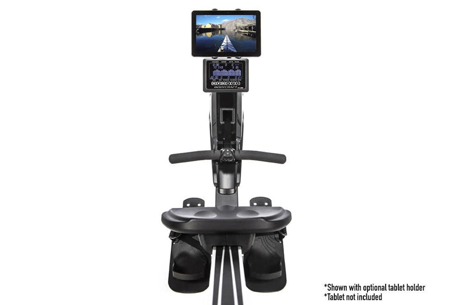 Black BodyCraft rowing machine with digital display console, tablet holder mount, and dual foot pedals on white background