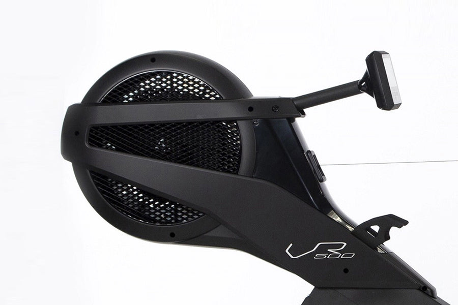 Black rowing machine with perforated seat bucket, extending arm with digital display monitor, and V500 logo on footrest again