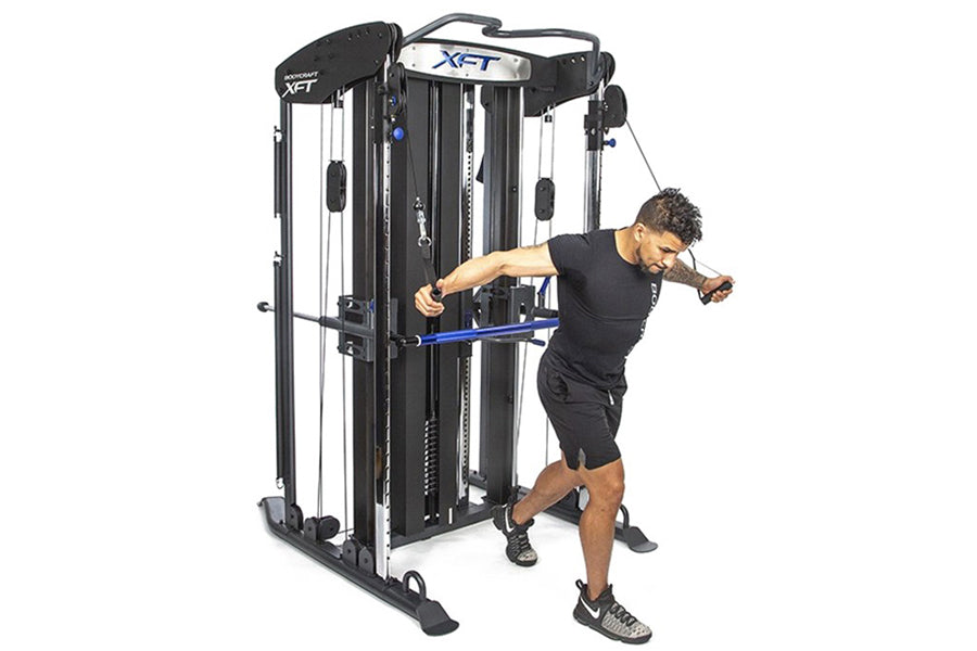 BodyCraft XFT functional trainer with black and white frame, shown being used by male model in black shirt performing cable e