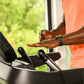 Person wearing orange shirt and black smartwatch using Bowflex T16 treadmill with hand on console near window