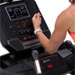 Person wearing coral sports bra using BowFlex T9 treadmill with digital display console and red accent trim, shown from side 