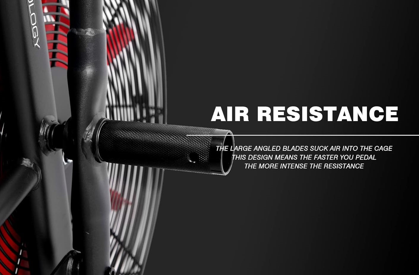 Stationary exercise bike with gray frame, black textured pedals, and red and white fan cage on dark background
