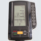 Black exercise bike console with LCD display showing time, distance, calories, watts, speed and RPM metrics, featuring orange