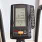 Black stationary exercise bike console with LCD display showing time, distance, calories, watts, speed, and RPM, with gray ha