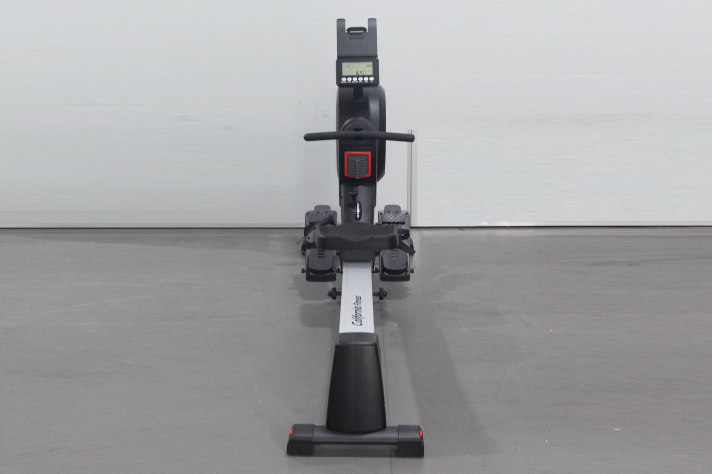 Black and white rowing machine with digital display console, handlebar, footrest pedals, and sliding seat on gray background