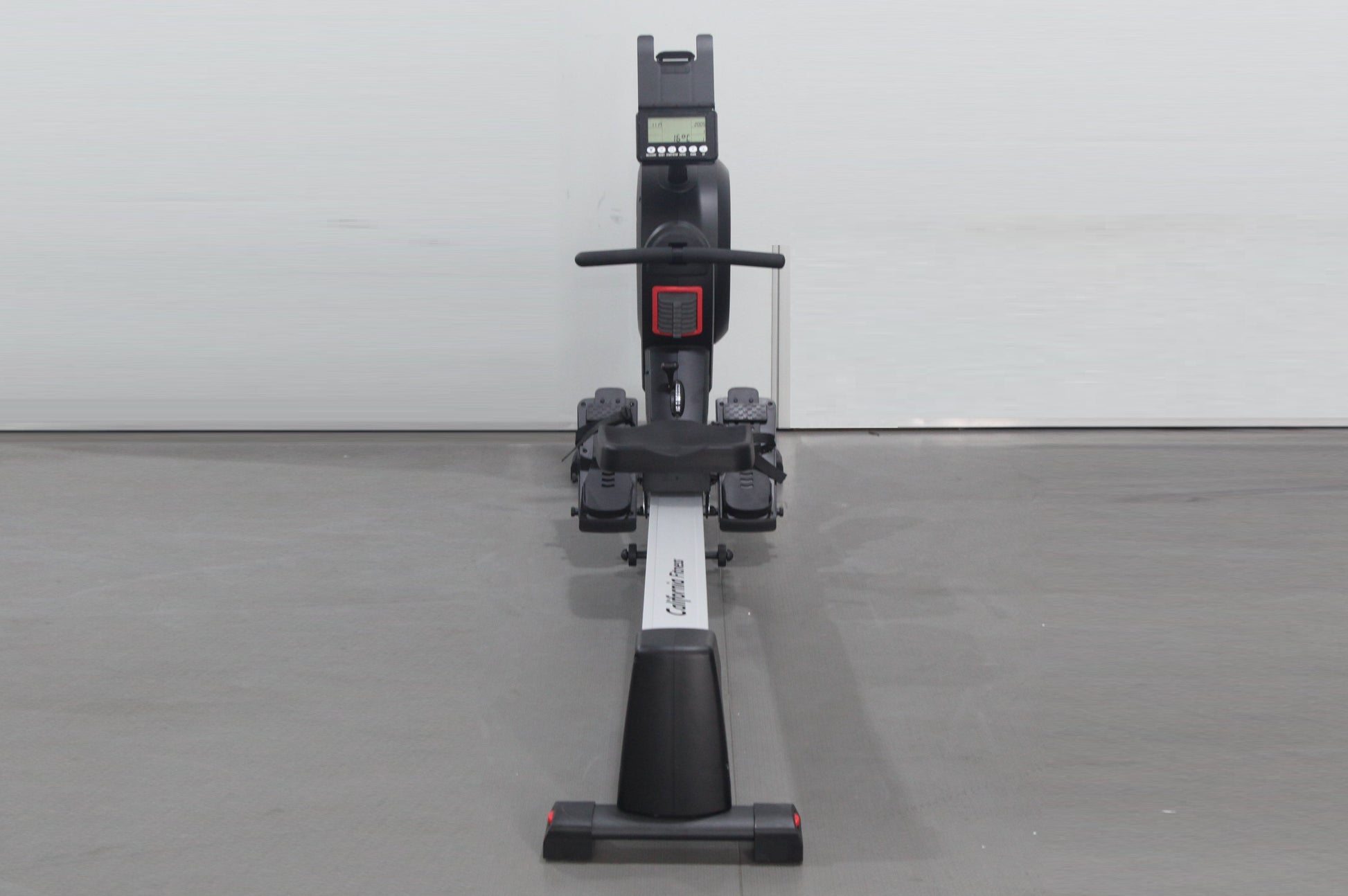 Black and white rowing machine with digital display console, handlebar, footrest pedals, and sliding seat on gray background