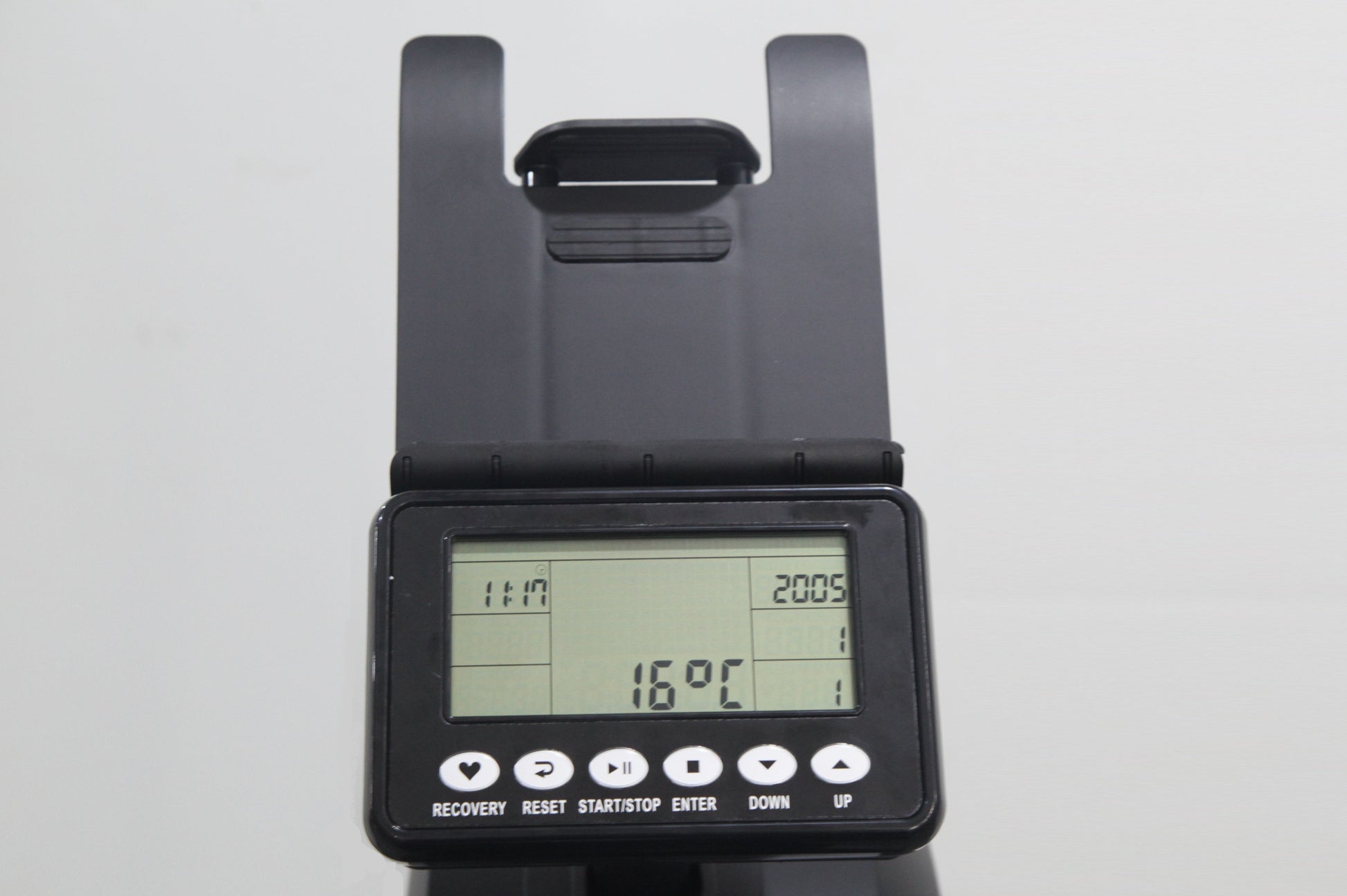 Black rowing machine console with LCD display showing time, distance, and calorie metrics, adjustable arm handles, and contro