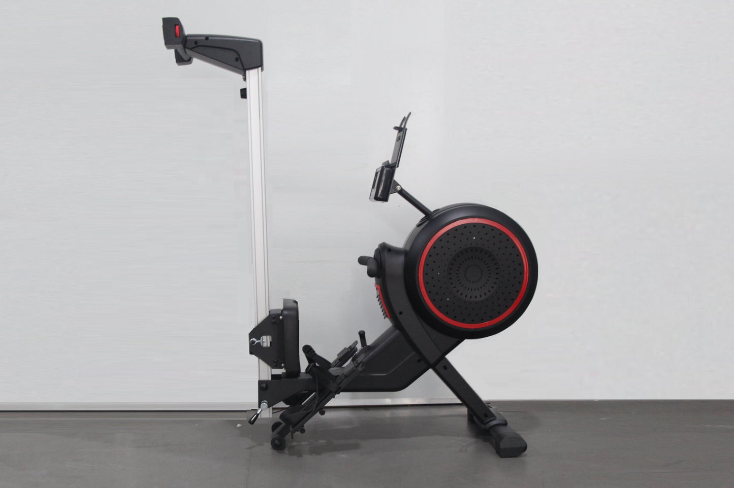 Black and red rowing machine with silver vertical rail, large circular flywheel with red accent ring, and adjustable footrest