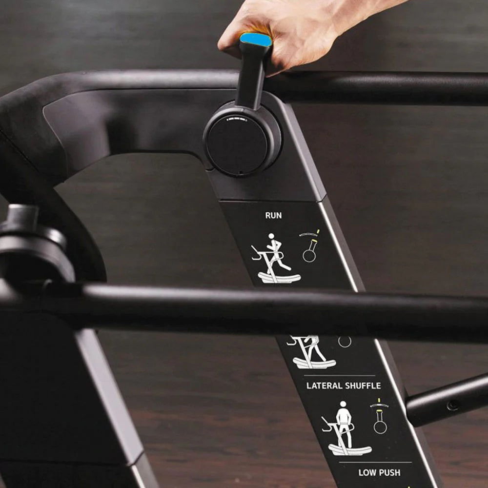 Black treadmill console with blue handlebar grip, displaying Run, Lateral Shuffle, and Low Push workout modes, held by hand