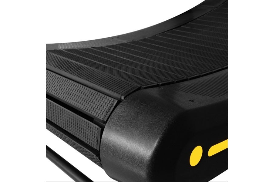 Black curved treadmill belt with textured running surface and yellow accent details on side panel