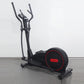 Black elliptical cross-trainer with red accents and curved handles, displayed on gray floor against white background