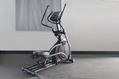 Black and silver elliptical machine with red accents and digital display on concrete floor