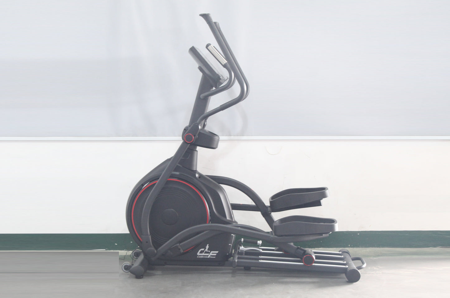 Black elliptical machine with red accent trim, dual handlebars, and padded seat on white background
