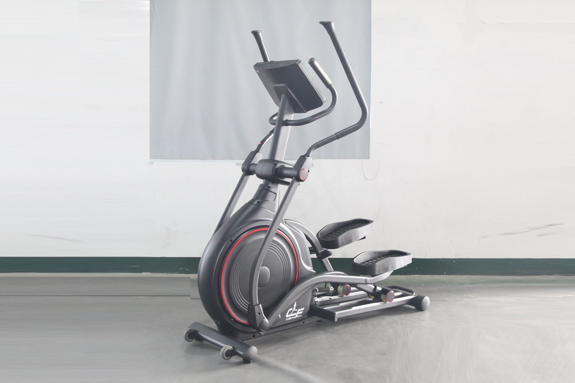 Black and gray stationary elliptical trainer with red accent trim and dual handle bars, displayed on concrete floor