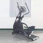 Black elliptical incline trainer with red accents, curved handles, digital display console, and extended footplate on gray fl