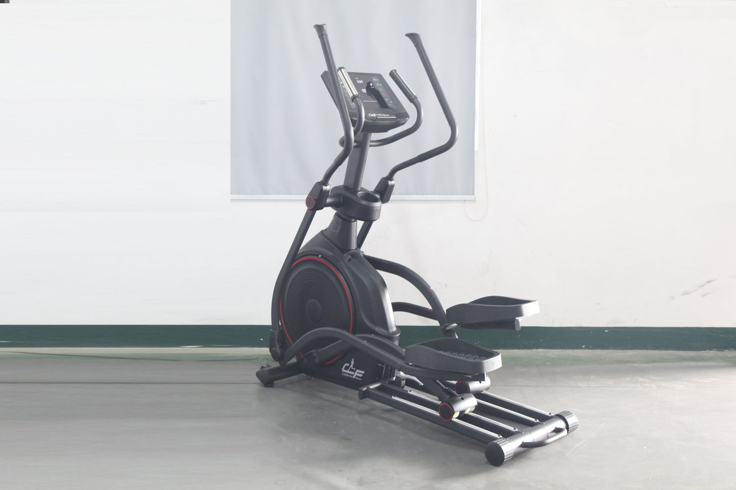 Black elliptical incline trainer with red accents, curved handles, digital display console, and extended footplate on gray fl