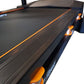 Black folding treadmill with orange trim and accents, featuring textured running belt and side controls, shown on white backg