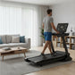 Man running on black folding treadmill with digital display in modern living room setting